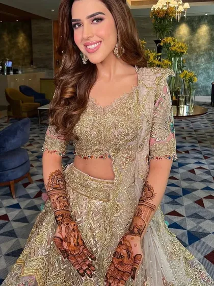 A beautiful bride in her wedding lehenga, proudly showing her detailed mehndi.