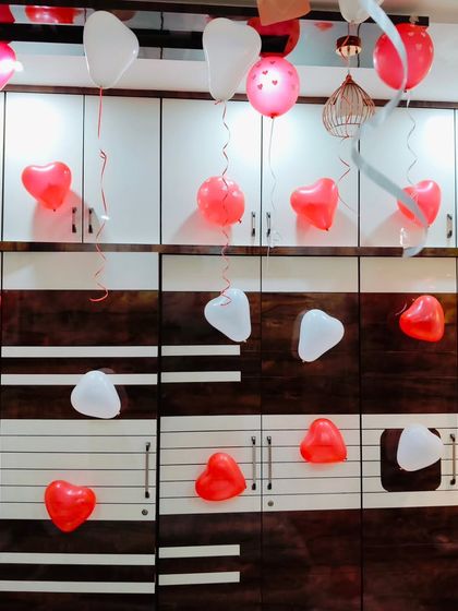 Simple and sweet romantic decor with red and white heart-shaped balloons floating on the ceiling and attached to the wall.