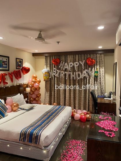 This image focuses on the "Happy Birthday" foil balloon setup against the curtains, part of a comprehensive hotel room surprise package.