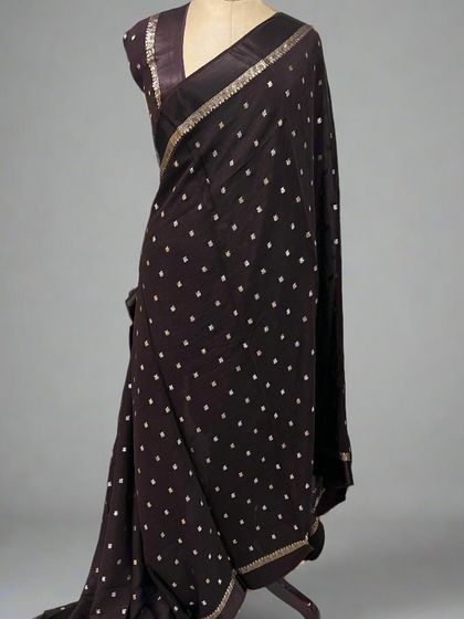 A beautiful Chinnon saree with a satin border in a deep brown, draped on a mannequin.