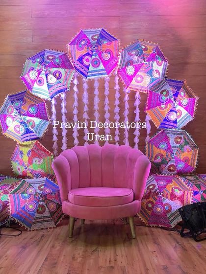 A fun and quirky Mehendi seating idea. We used a comfortable pink armchair surrounded by colorful Rajasthani umbrellas and a curtain of white flowers, creating a perfect spot for the bride.