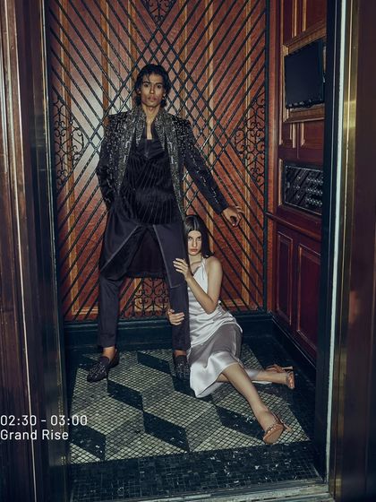 A moment of grand rise. This ensemble features a deep wine, longline jacket with shimmering, pixelated embroidery, creating a look of edgy elegance. It is designed for making a powerful entrance.