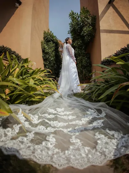 A wide shot showcasing the magnificent length and detail of the bride's lace veil, creating a dramatic and beautiful bridal portrait.