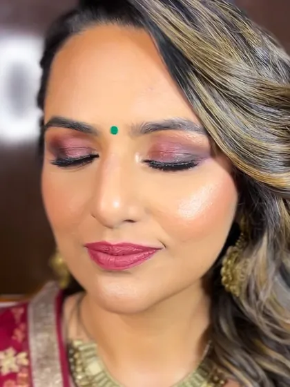 A close-up of this beautiful party makeup. The shimmery maroon and gold eyeshadow adds a touch of drama, while the highlighter gives her skin a beautiful glow.