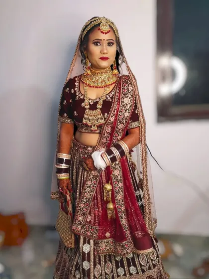 A full-length view of the bride in her maroon lehenga, showing how the makeup and outfit create a cohesive and royal look.