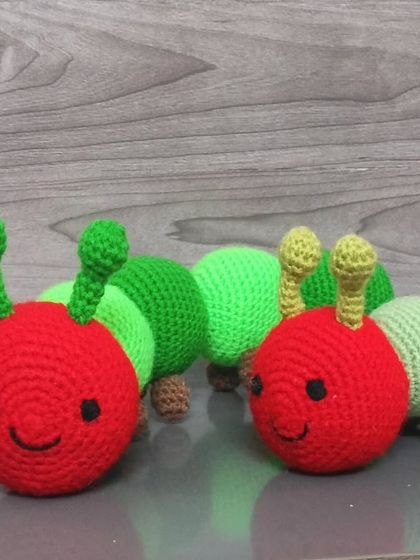 A pair of my new caterpillar toys. They have red heads and green bodies, just like the hungry caterpillar from the storybook.