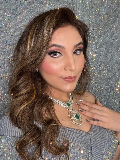 The client's hair is styled in beautiful, flowing waves that complement her off-shoulder top and statement necklace. This is a great hairstyle for a reception or cocktail event.