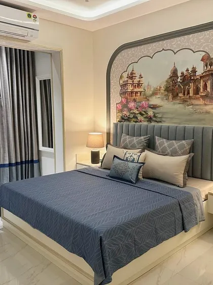 The master bedroom in the South Mumbai home, featuring a custom-painted mural of a heritage building within an arched niche. The serene blue bedding and elegant grey curtains create a sophisticated and artistic retreat.