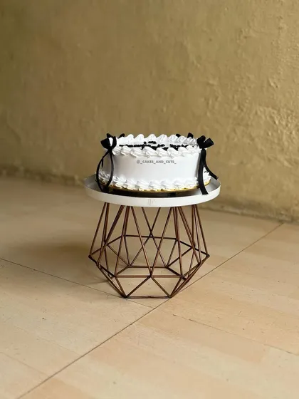 A full view of the classic vintage cake with black bows, sitting on one of our geometric stands.