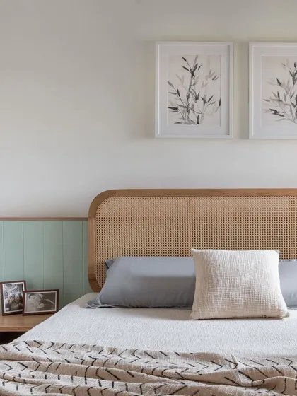 A close-up of the cane headboard and custom bedside table in the 'Living life in colours' primary room.