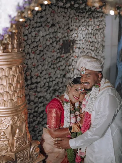 A joyful hug between the newlyweds. The backdrop of flowers and their happy faces perfectly capture the celebratory spirit of the wedding day.