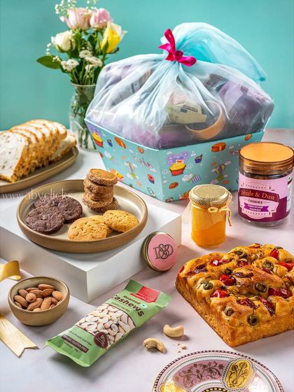 A large, beautifully wrapped gift hamper from Drizzle & Dust, filled with baked goods and snacks.
