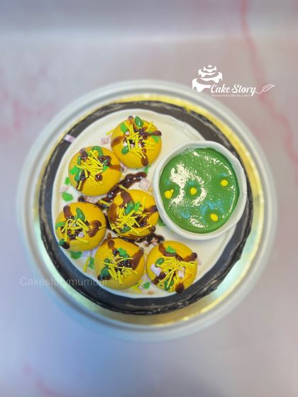 A top-down view of the incredible Pani Puri cake, showing the detailed puris, the bowl of green pani, and tamarind chutney drizzle.