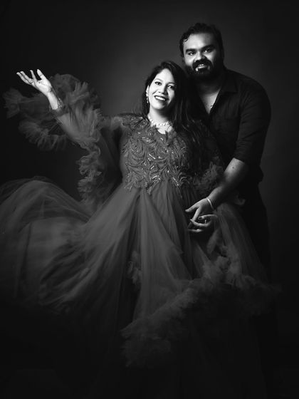 This black and white photograph of a couple captures a moment of shared joy. The flowing red gown provides beautiful texture and drama, creating a timeless and artistic portrait.