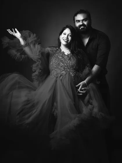 This black and white photograph of a couple captures a moment of shared joy. The flowing red gown provides beautiful texture and drama, creating a timeless and artistic portrait.