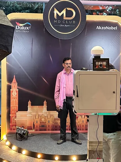 A close-up of the photo booth setup for the AkzoNobel and Dulux MD Club event, showing a guest posing against the branded backdrop.