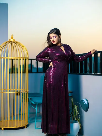 A full-length view of a glamorous evening look. The makeup features a dramatic purple smokey eye that perfectly matches the model's sequined gown.