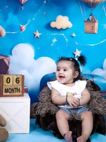 Celebrating a six-month milestone with our popular teddy bear and clouds theme. Her happy expression shows how much fun these sessions can be.