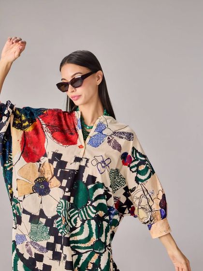 A model looks effortlessly cool in an oversized shirt dress with a bold, abstract print, paired with cat-eye sunglasses.
