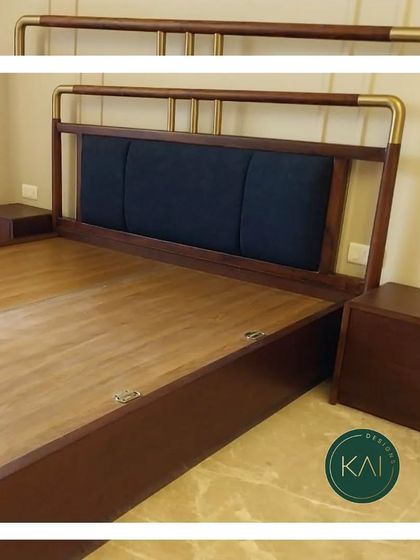 A custom bed frame made from rich, dark wood with a contrasting navy blue upholstered panel in the headboard. The brass-finished metal railing adds a touch of classic elegance to this sturdy and stylish piece.