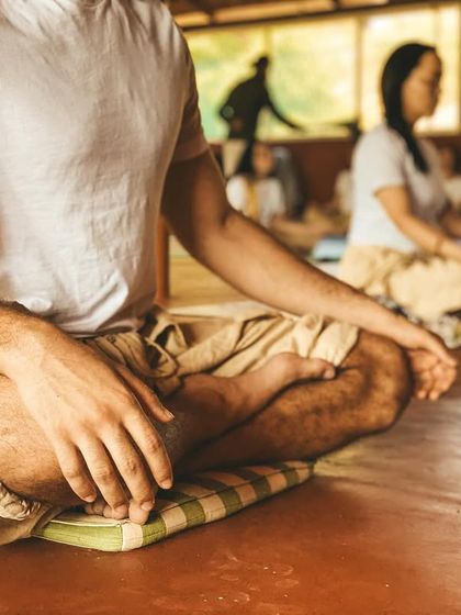 A student sits in quiet meditation, hands resting in Gyan Mudra. In these moments of stillness, we move beyond the body and mind to touch the silence within. This is the true goal of yoga.