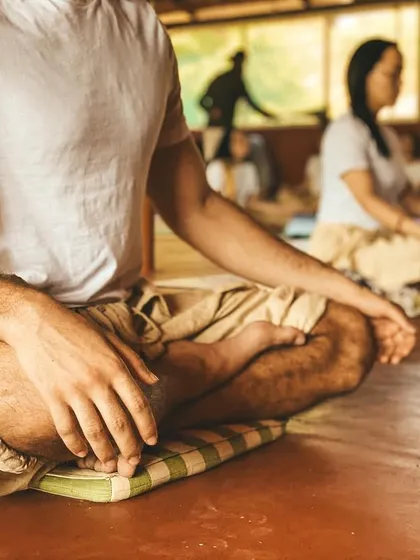 A close-up of a student in meditation. The focus is on finding comfort in stillness, which is the true purpose of asana practice: to prepare the body for long periods of spiritual inquiry.