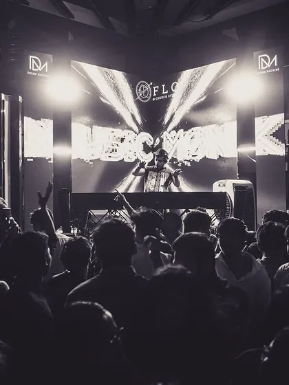 A black and white shot from the stage at Flo, capturing the classic DJ silhouette against a massive crowd. It's a timeless image of a DJ commanding the room.