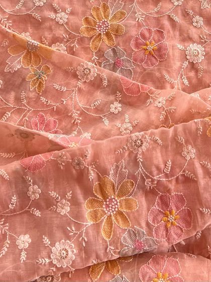 A closer look at our embroidered Mul Chanderi in a soft peach. The multi-colored floral embroidery creates a beautiful, garden-like effect on the sheer fabric.