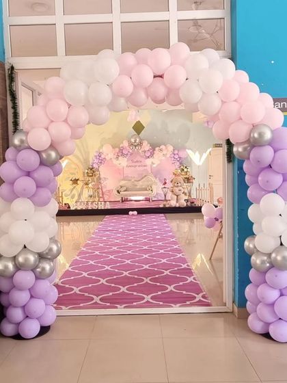 A beautiful balloon arch in pastel purple, pink, and white, leading guests into a butterfly-themed party.