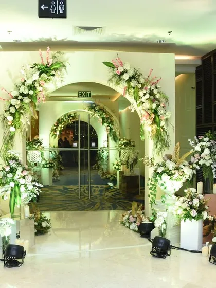 A series of clean, white arches adorned with florals creates a modern and sophisticated corridor, guiding guests into the main celebration space.