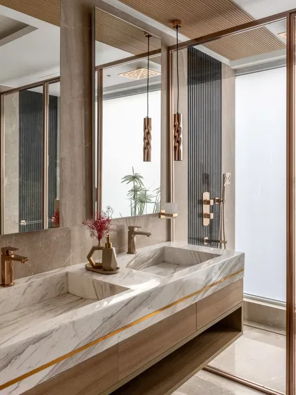 This bathroom highlights our focus on material excellence and detailed craftsmanship. We combined a custom-carved marble double sink with warm wood cabinetry and rose gold fixtures, creating a functional space that feels like a private, luxurious retreat.