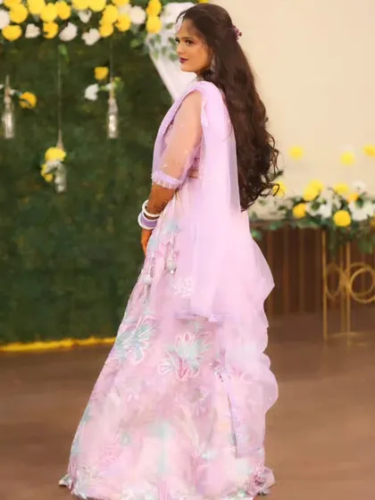 A back view of the bride, showing off her long, flowing hair and the elegant design of her lehenga.