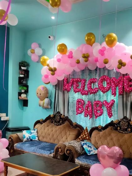 A close-up of the "Welcome Baby" living room setup, showing the balloon arch over the sofa.