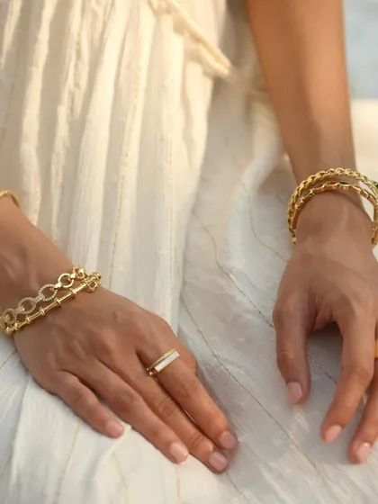 A beautifully styled shot of our gold cuff bangles and rings. The mix of a plain clover bangle with a chunky link cuff creates a balanced and stylish look.