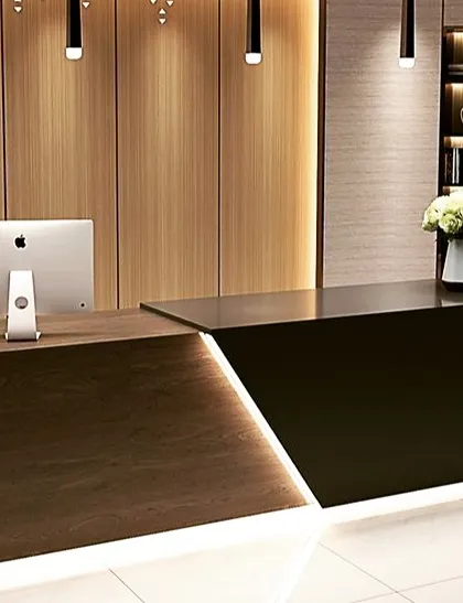 A sleek, two-tone reception desk in dark wood and black, with integrated LED lighting creating a sharp, modern look. This design is ideal for a contemporary corporate office or studio.