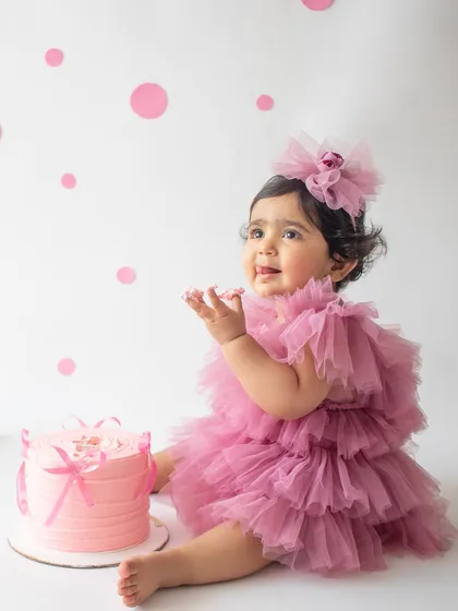 A first birthday is a huge milestone, and a cake smash is the perfect way to celebrate. This little one is having the best time with her very own pink cake in a clean, minimalist setup.