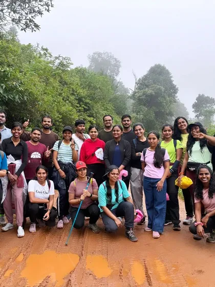 A group photo on a muddy trail, with everyone equipped with trekking poles and ready for the challenge.