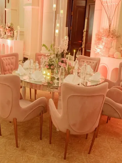 The dining setup for the ring ceremony featured elegant blush pink chairs around a mirrored table, with tall candelabras and floral centerpieces creating a sophisticated and intimate atmosphere.