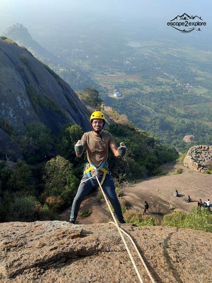 A trekker getting ready for his rappelling turn at Uttari Betta, with a stunning view of the valley below.