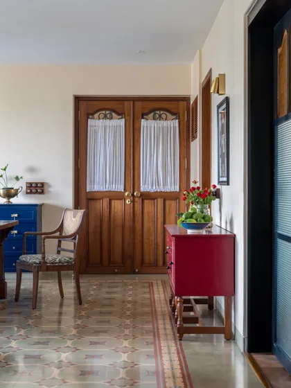 This Calcutta living room was designed to hold a family's energy and memories. We kept the soul of their old bungalow by using warm woods, patterned heritage tiles, and pops of color like this red console. The goal was to create a space that feels generous and grounded, where stories can be passed down for generations.