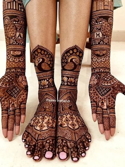 A complete bridal look, this photo shows the coordinated mehendi on hands and feet, featuring peacocks and personalized initials.
