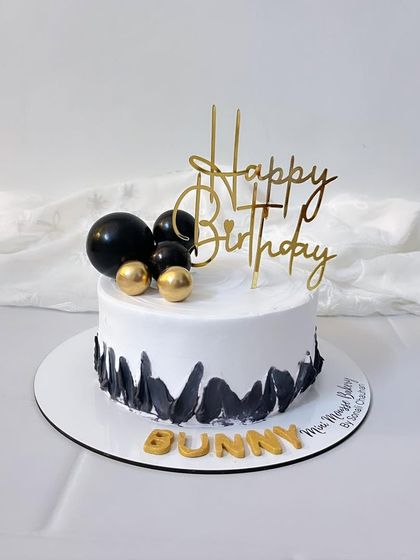 A simple and elegant birthday cake in black, white, and gold. The abstract black brushstrokes give it a modern, artistic feel.