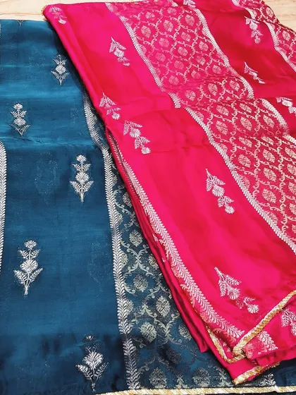 A beautiful display of our festive collection fabrics. The rich teal and vibrant pink soft silks with silver zari work show the variety of colors and designs you can choose from.