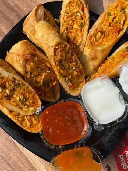 My crispy spring rolls are fried to a perfect golden brown and filled with a savoury mix of shredded vegetables. They are served with sweet chilli sauce and a creamy dip, making for a delicious appetizer.