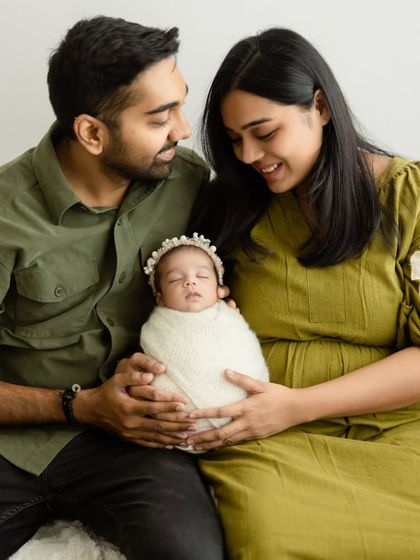 Parents looking down at their newborn with loving smiles. This shot captures the quiet wonder of welcoming a new life into the family.