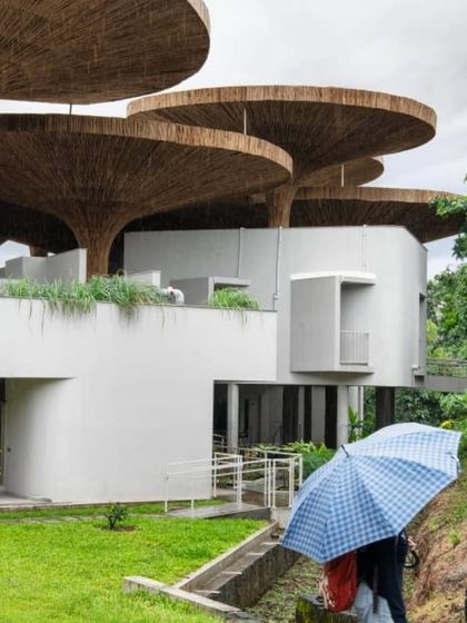 The layered parasols of the TAPMI Centre seen from the ground, creating a dynamic roofscape that interacts with the natural environment. The design is both functional and poetic.