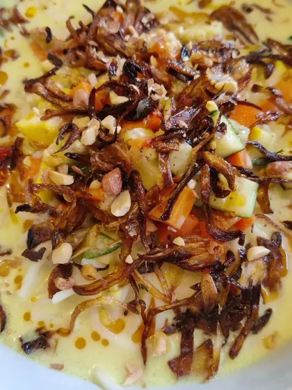 Our vegetarian Khao Suey is a meal in a bowl. This image shows the creamy coconut curry topped with crispy fried onions and peanuts, adding a wonderful texture to the dish.