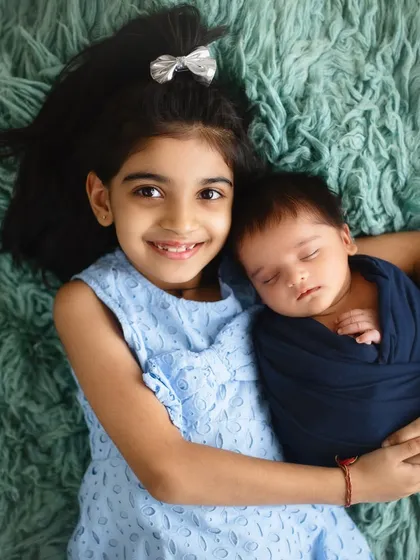 A big sister's proud smile as she holds her newborn brother. Sibling photos are a precious part of my newborn sessions, capturing the start of a lifelong friendship.