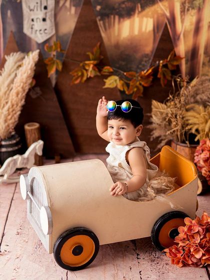 A cool little guy waving from his vintage toy car. Props are a great way to add a story and a sense of fun to your baby's milestone photos.