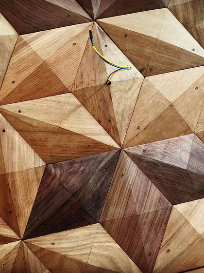 A close-up of a 3D geometric wood panel, showing the precise cutting and arrangement of different wood veneers. This kind of detail adds incredible texture and depth to a surface.